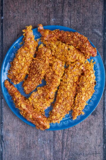 Eight coated chicken tenders on a blue plate.
