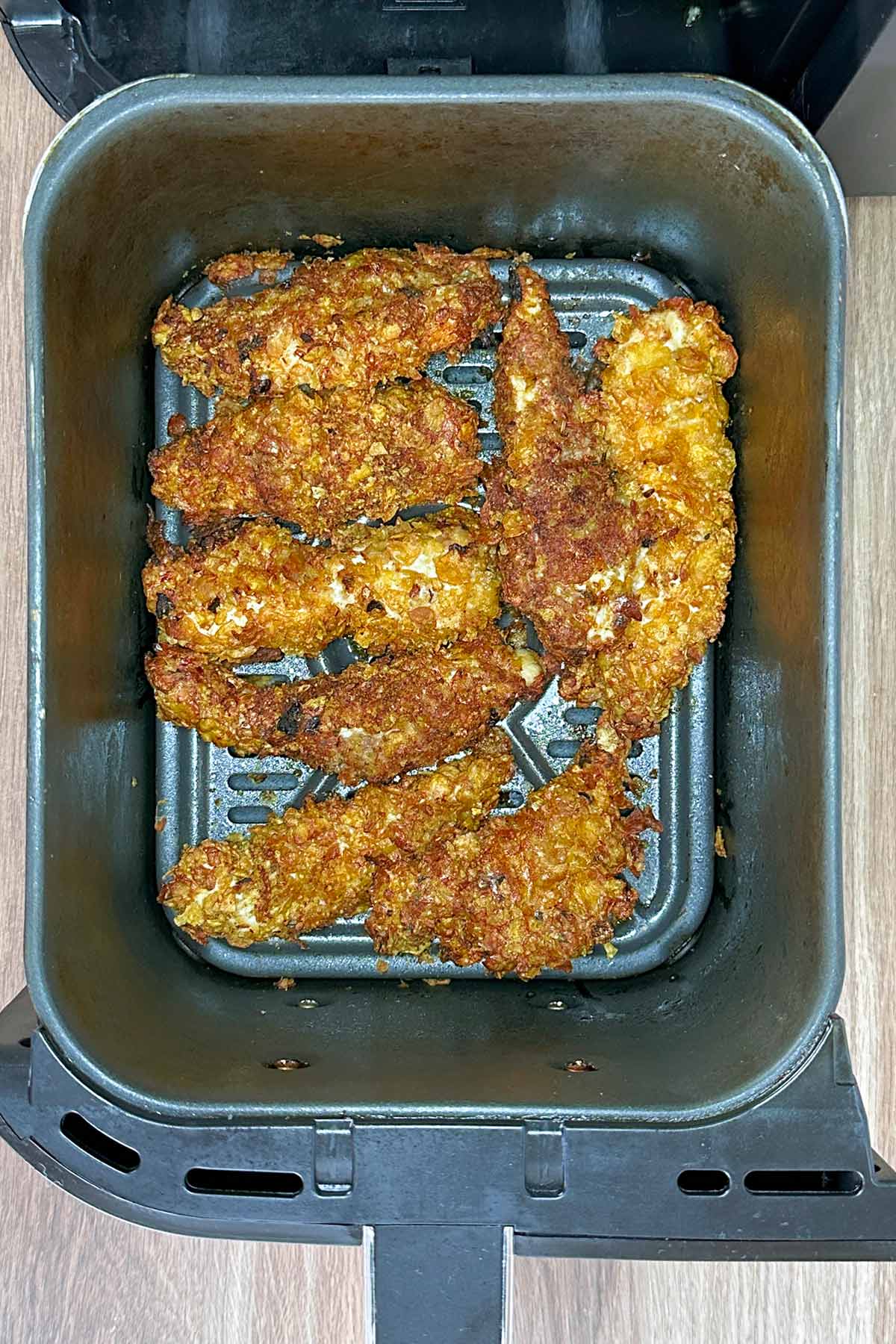 Cooked chicken tenders in an air fryer basket.