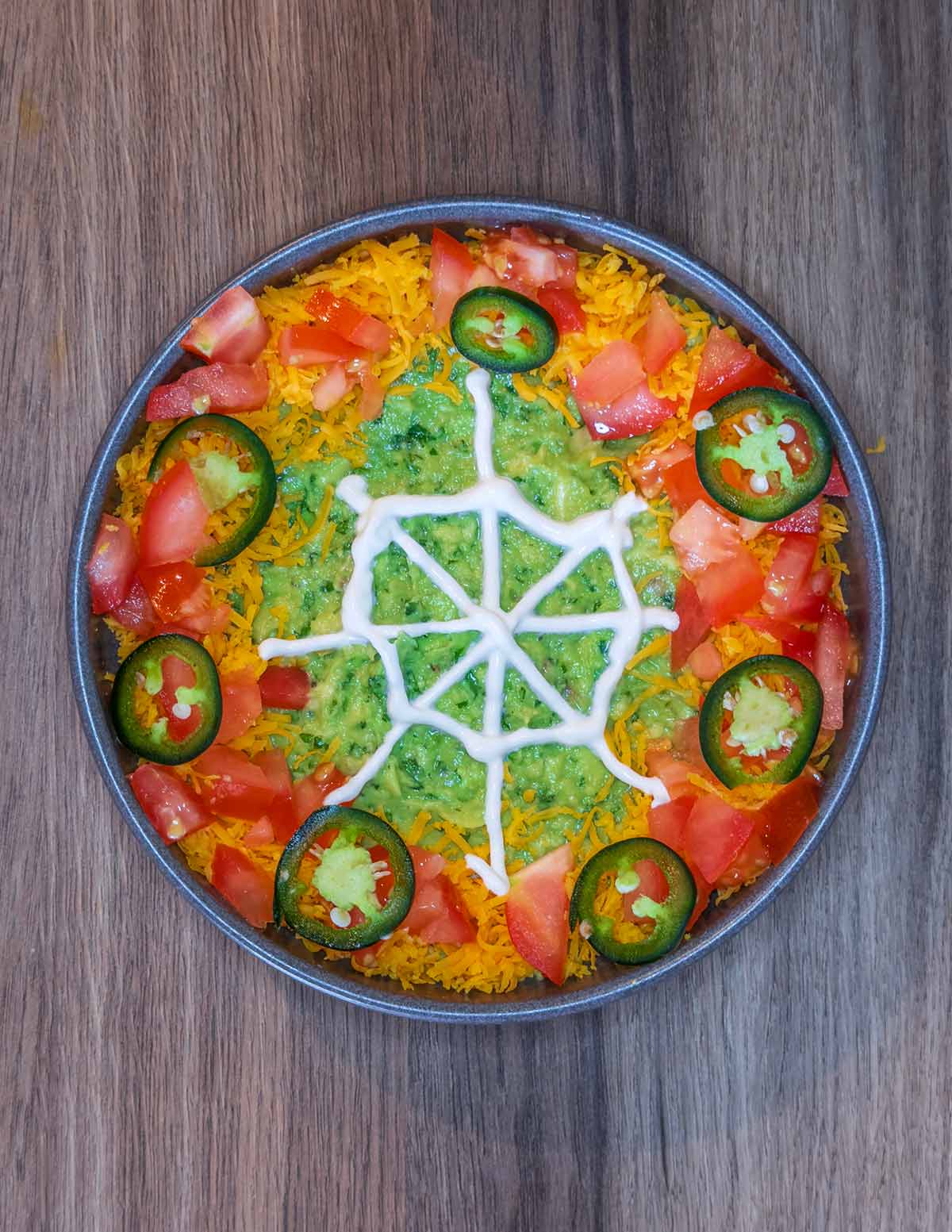 A spider's web drawn in sour cream on top of the guacamole.