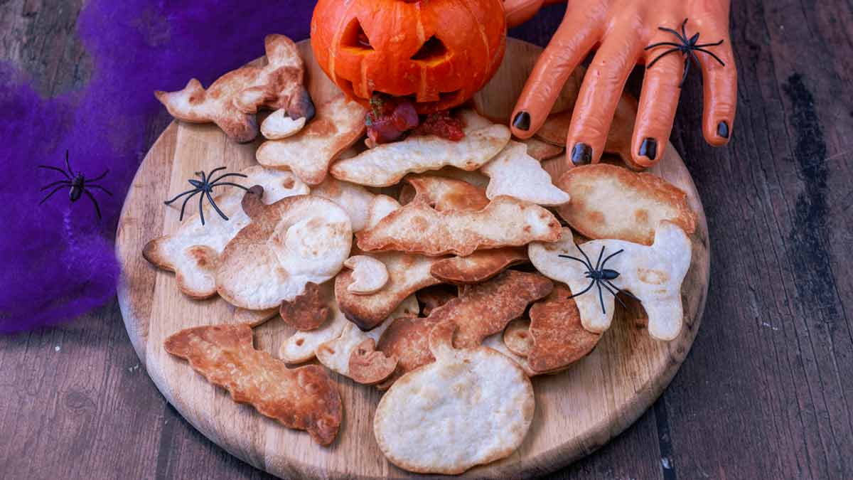 Halloween tortilla chips on a wooden board with a pumpkin.