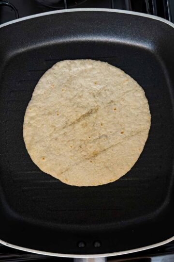 A mini tortilla wrap dry frying in a griddle pan.
