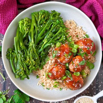 Sticky chicken meatballs on a plate with rice and broccoli.