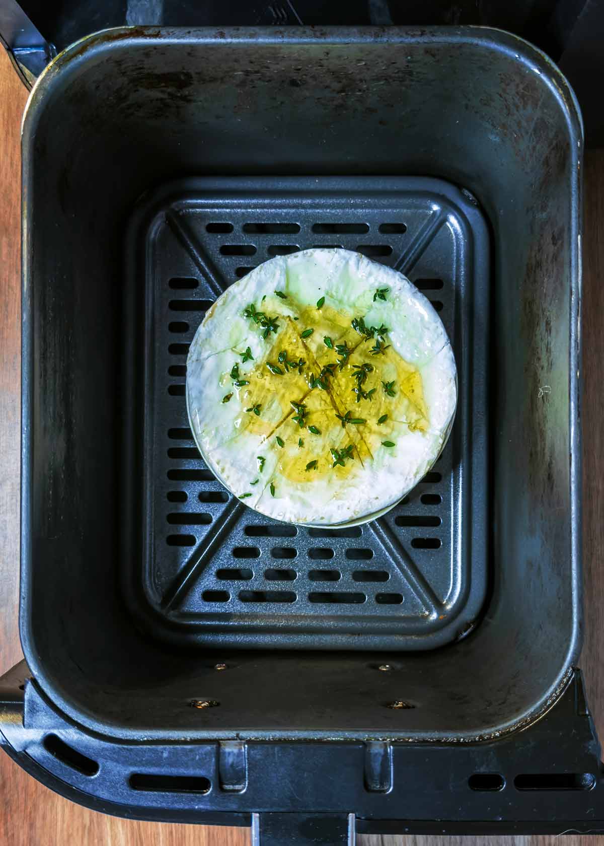 The uncooked Camembert in an air fryer basket.