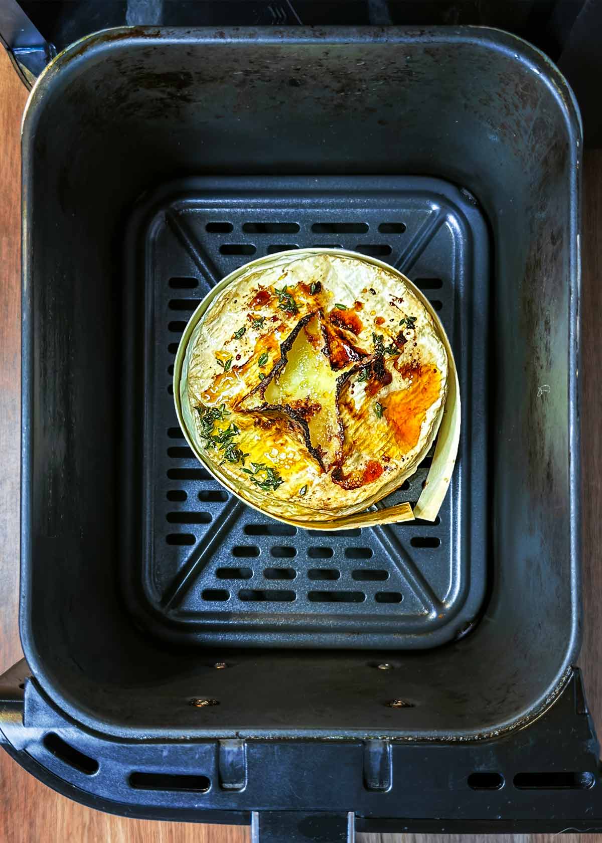 Cooked Camembert in an air fryer basket.