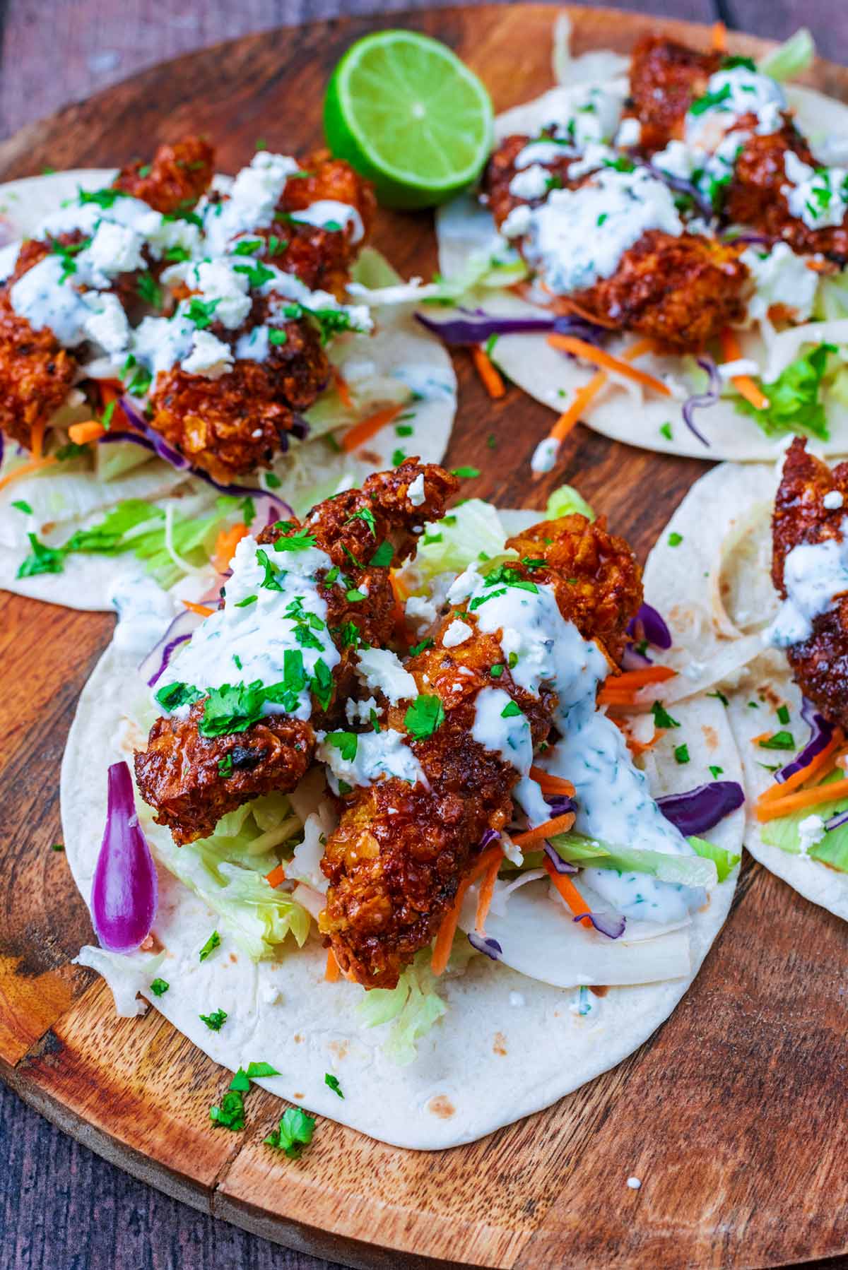 Four tacos made up of salad, crispy chicken tenders, creamy sauce and cheese.