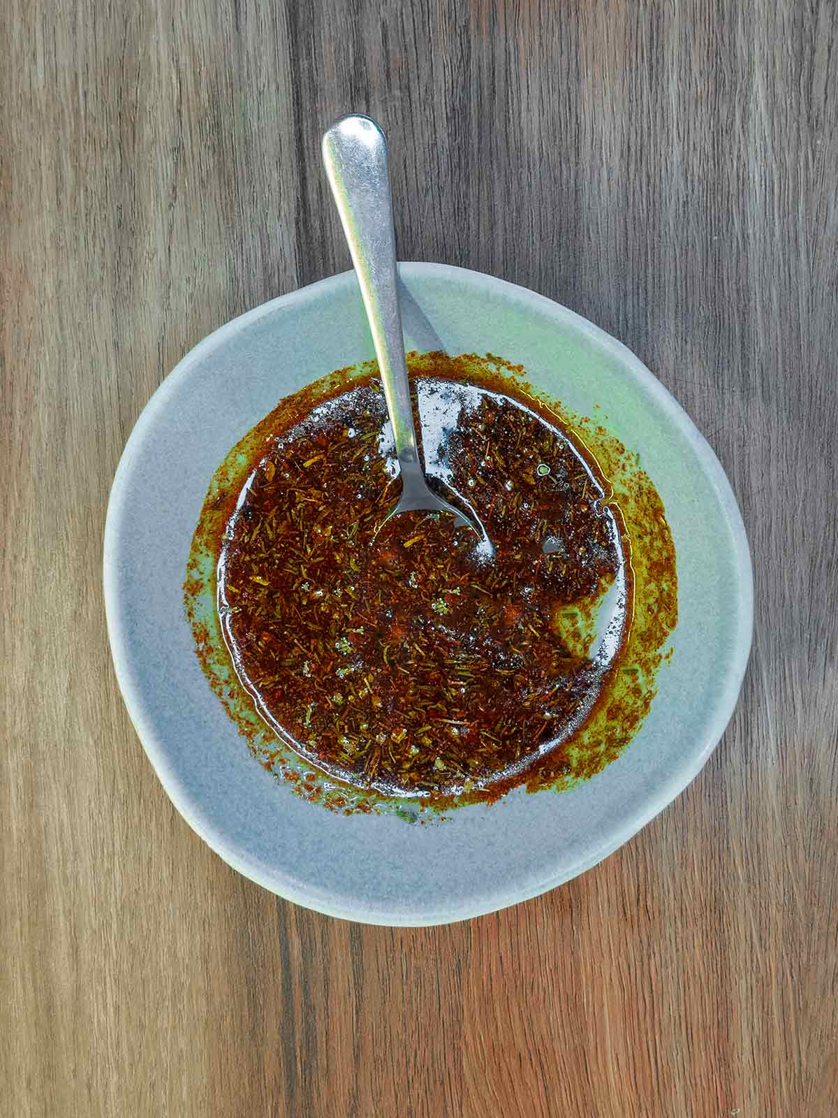 A small bowl containing a mixture of oil, herbs and spices.