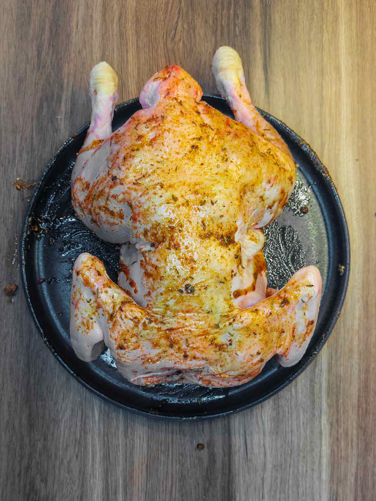 A whole chicken smothered in a spice rub.