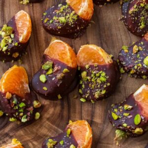 Chocolate covered orange segments on a wooden board.