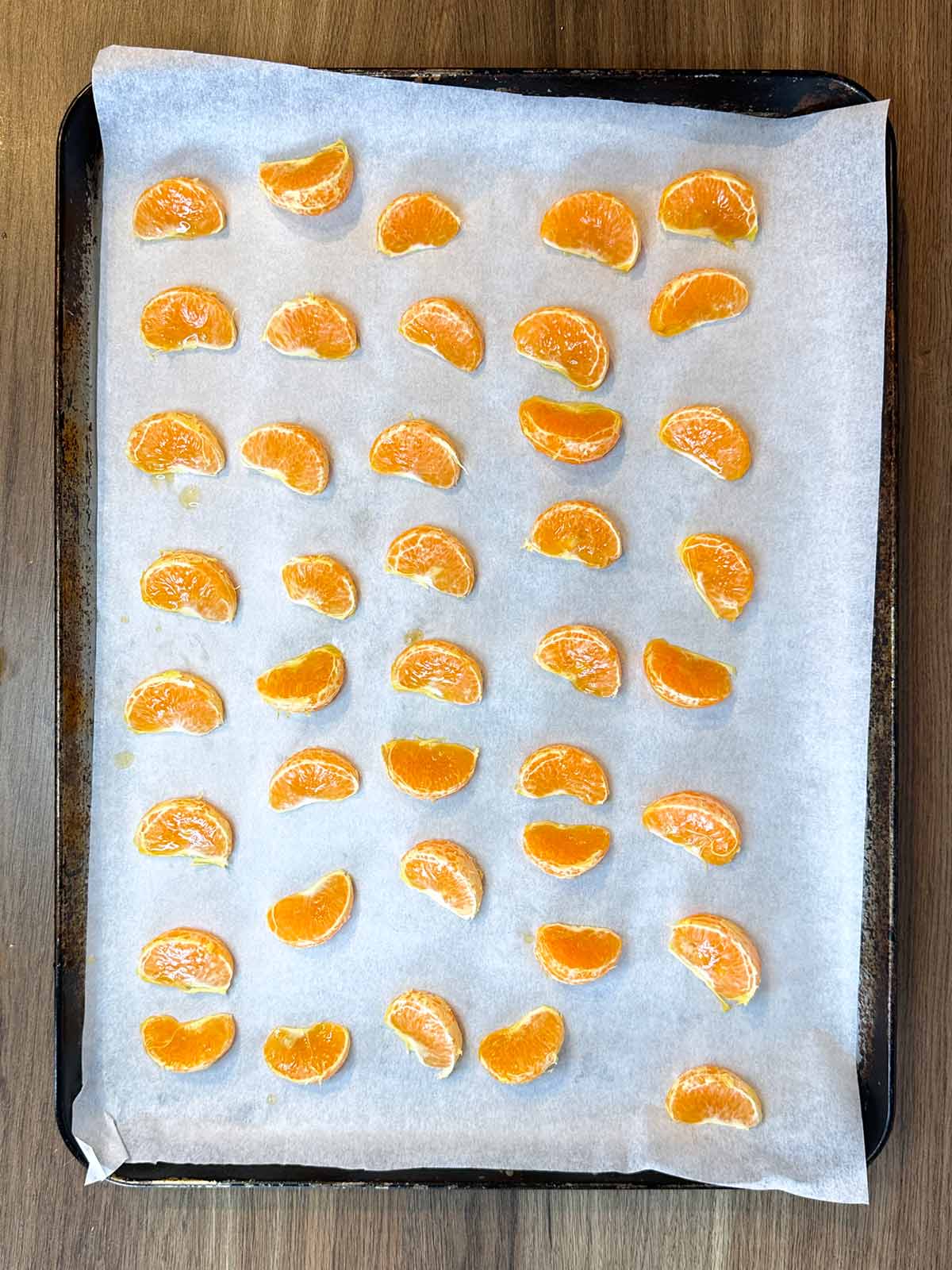 Satsuma segments laid out on a lined baking tray.
