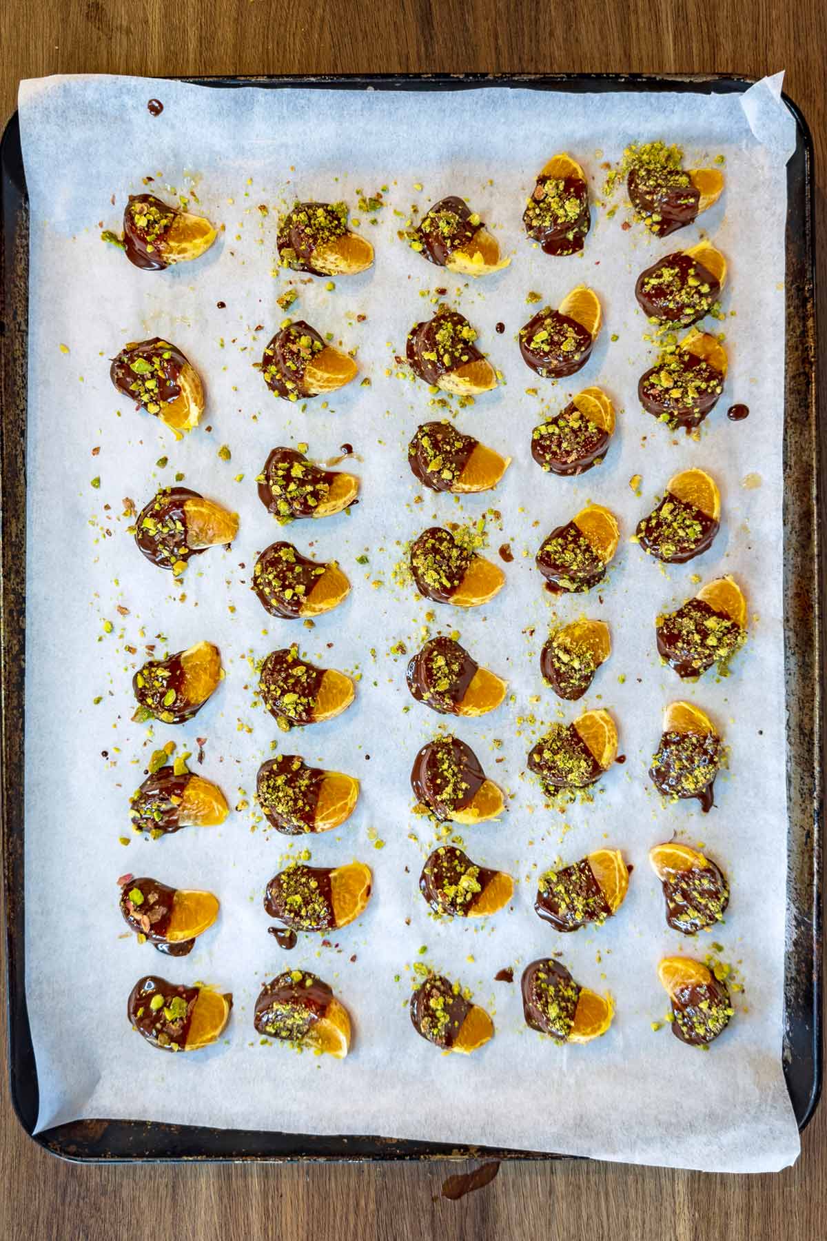 The satsuma segments half covered in chocolate and and sprinkled with crushed pistachios.