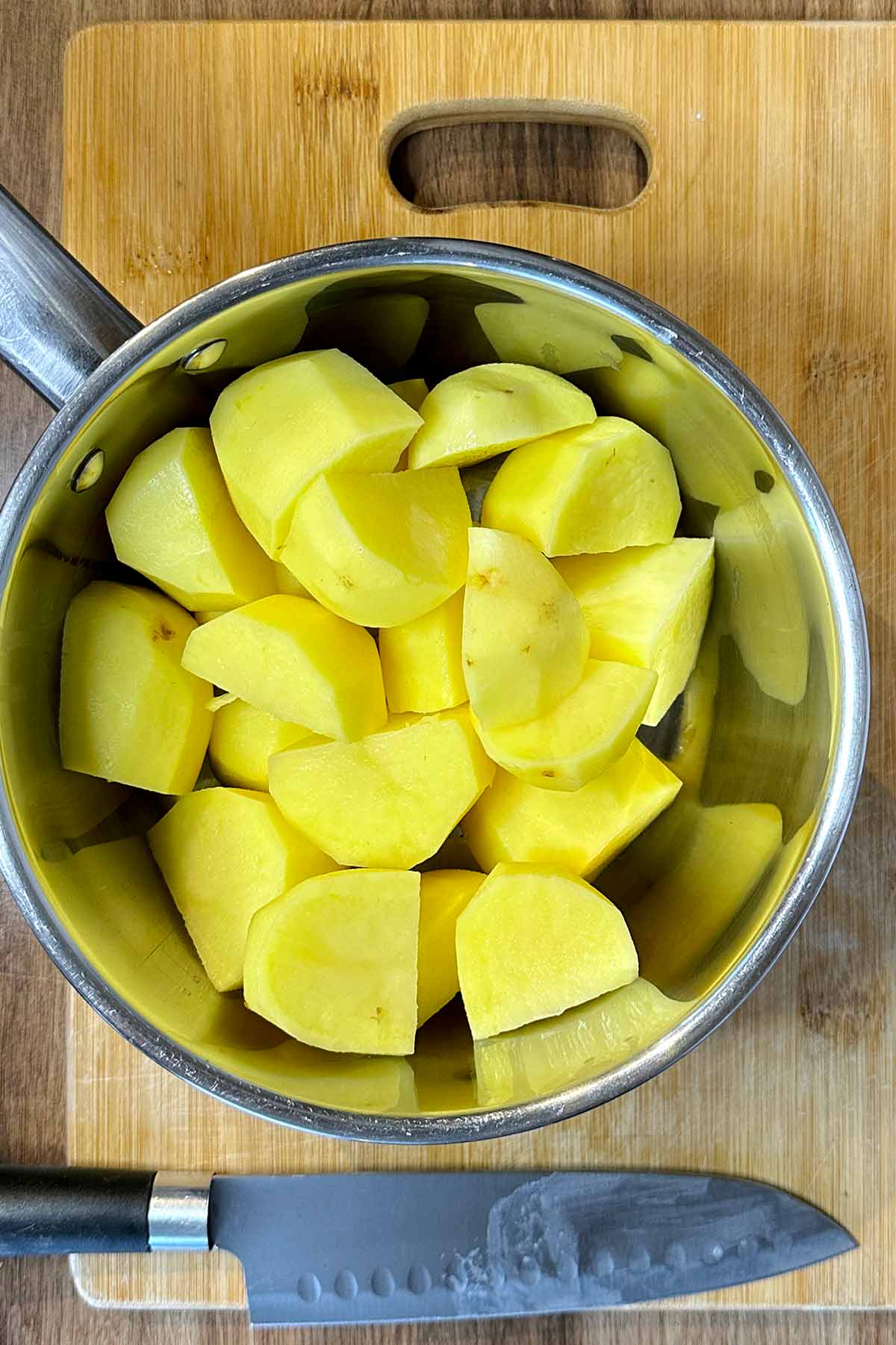 A pan of peeled and quartered potatoes.