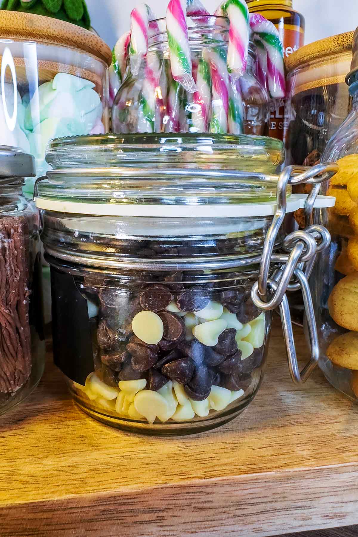 A glass jar full of dark and white chocolate chips.