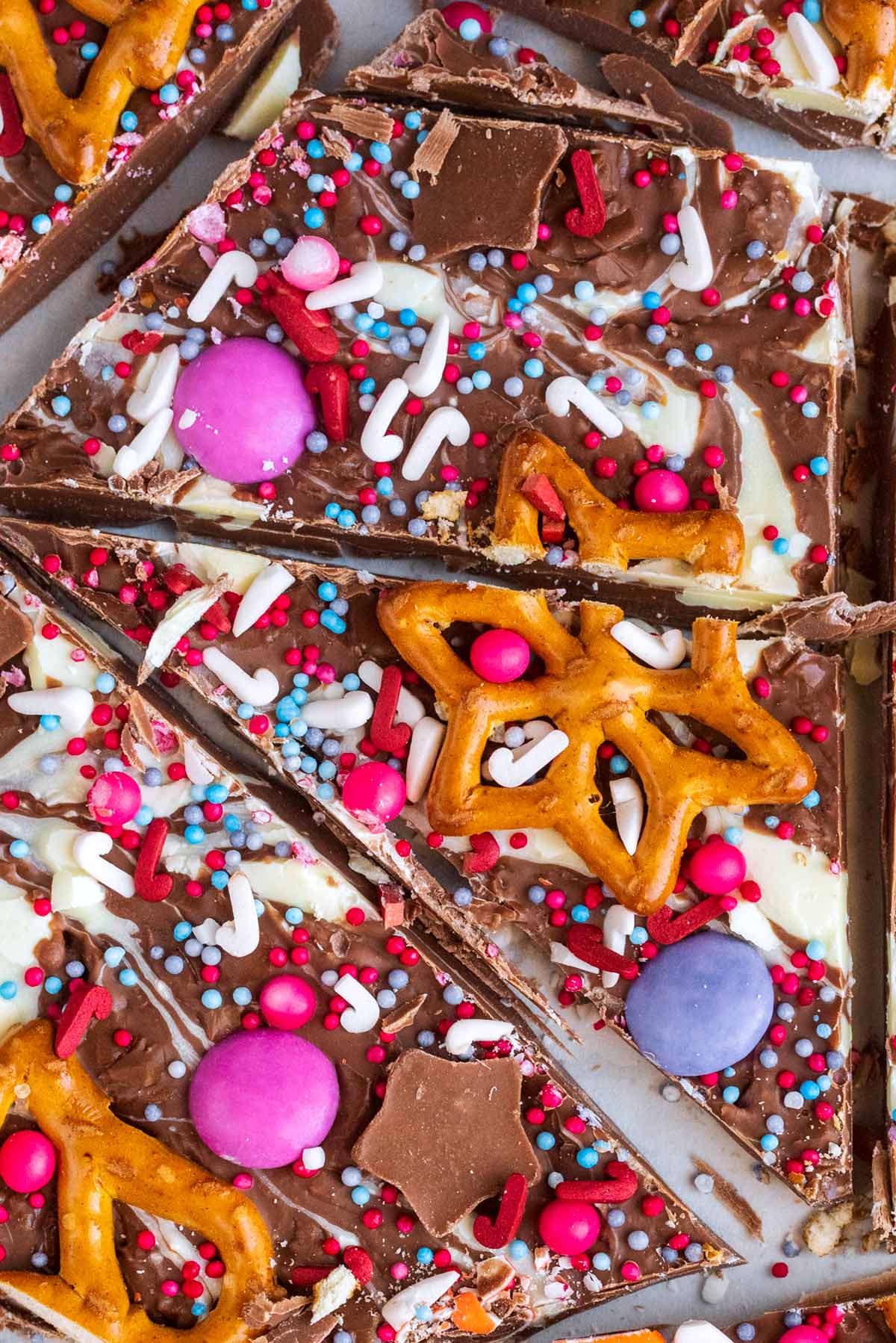 A star shaped pretzel, some Smarties and festive sprinkles on top of chocolate.