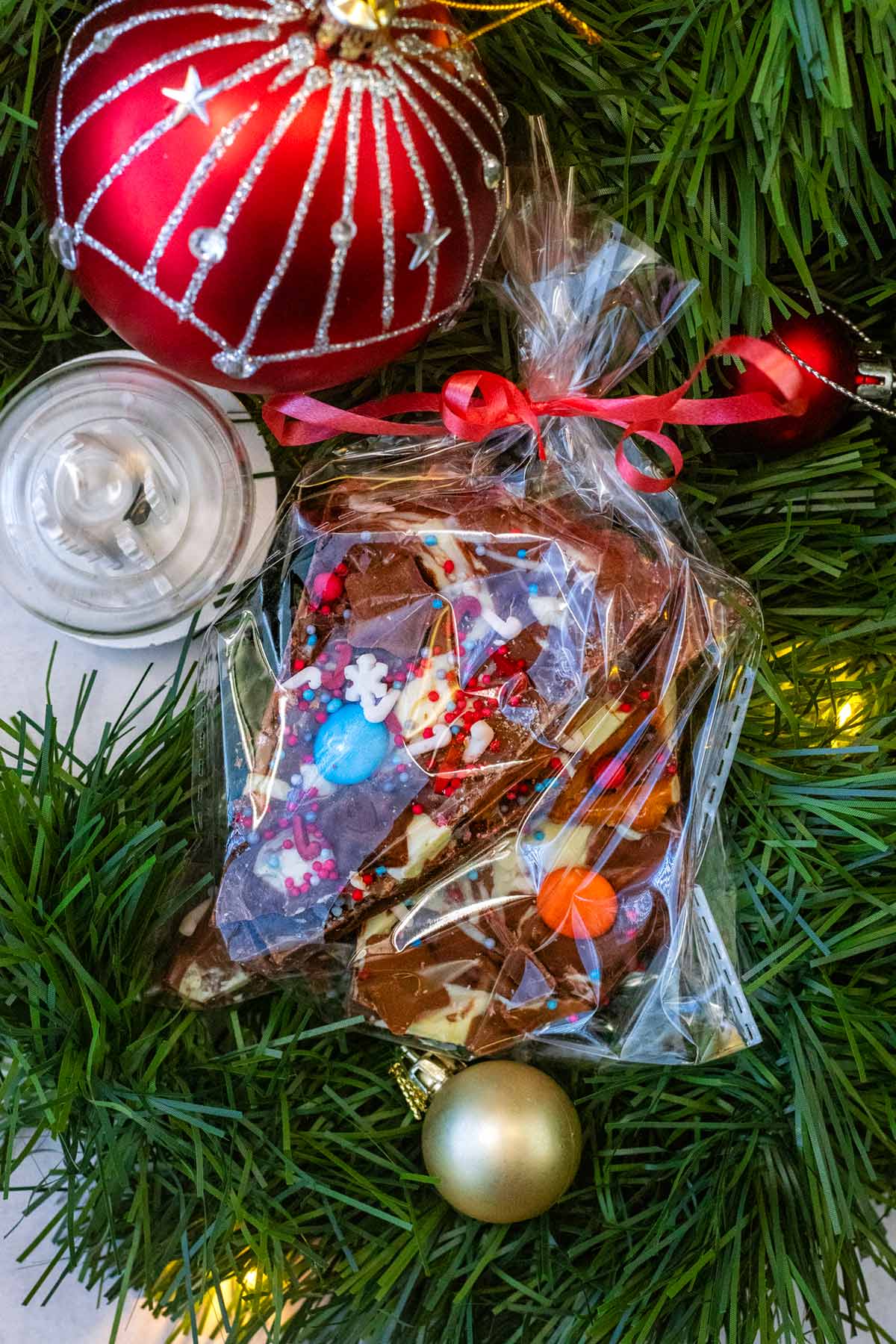 A cellophane bag full of chocolate bark surrounded by a Christmas garland.