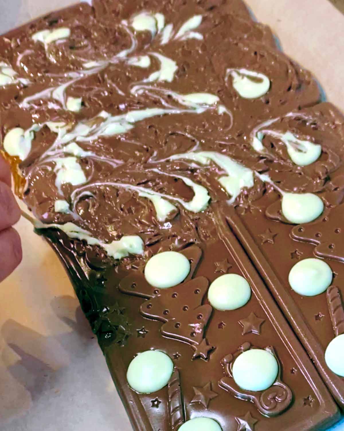 A hand swirling the melted chocolate with a cocktail stick.