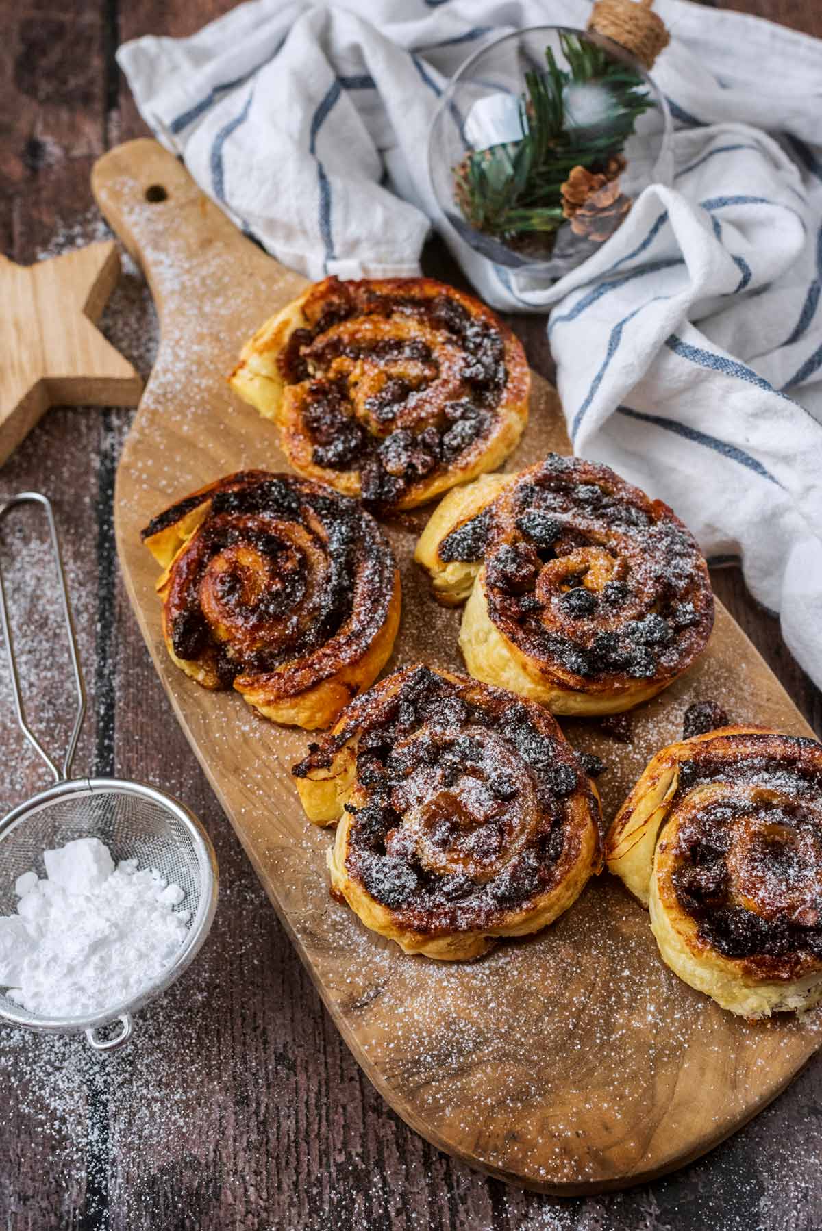 A board of mince pie pinwheels next to a striped towel and Christmas decorations.
