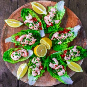 A circle of prawn cocktail canapes on a round wooden board.