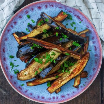Strips of air fryer aubergine on a blue plate.