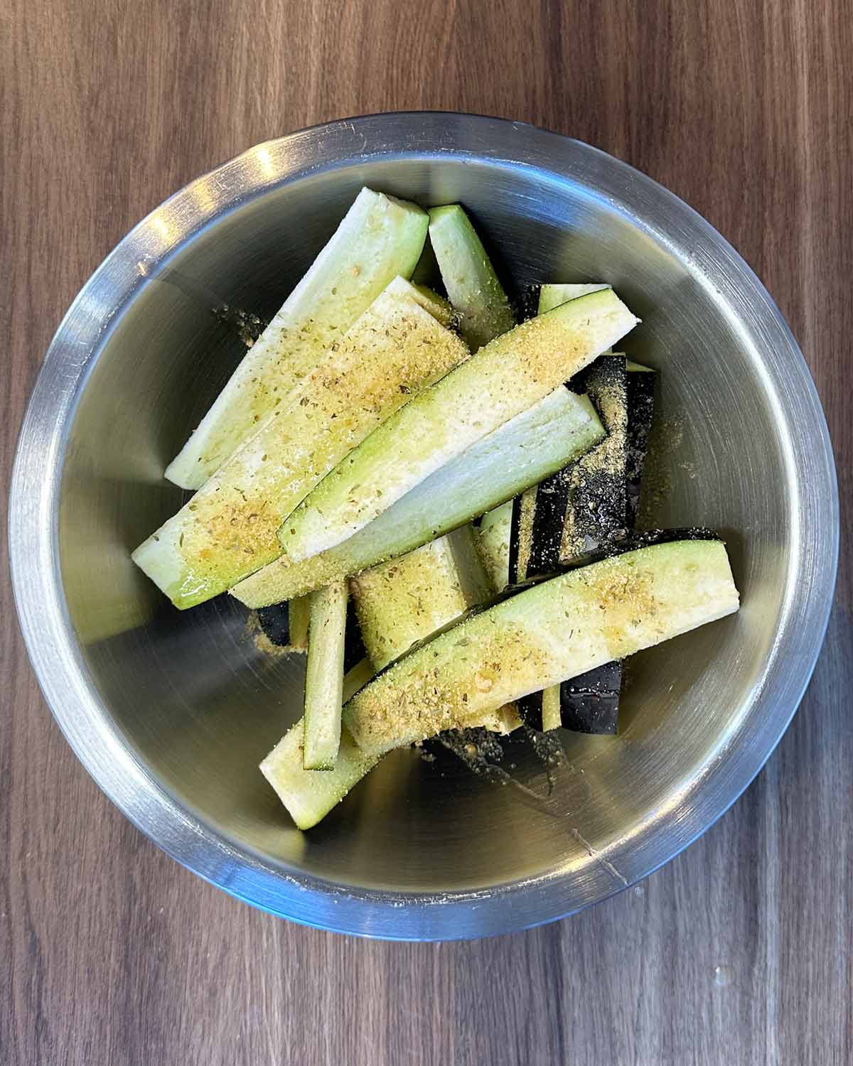 Aubergine strips in a bowl with oil and seasoning.
