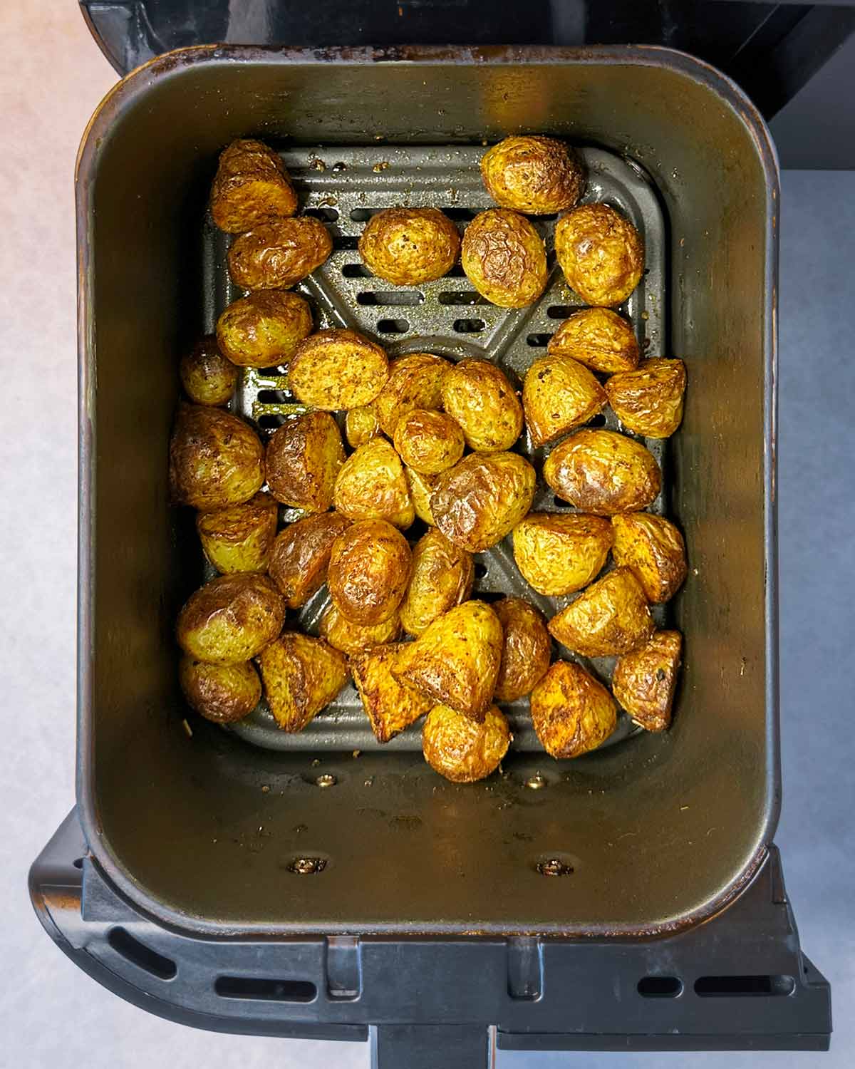 Cooked baby potatoes in an air fryer basket.