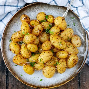 Air fryer canned potatoes on a plate topped with chopped herbs.