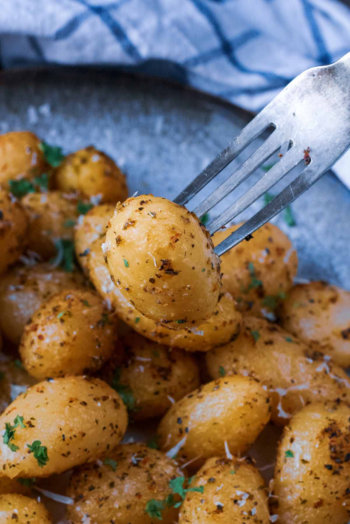 A fork in a cooked and seasoned new potato.
