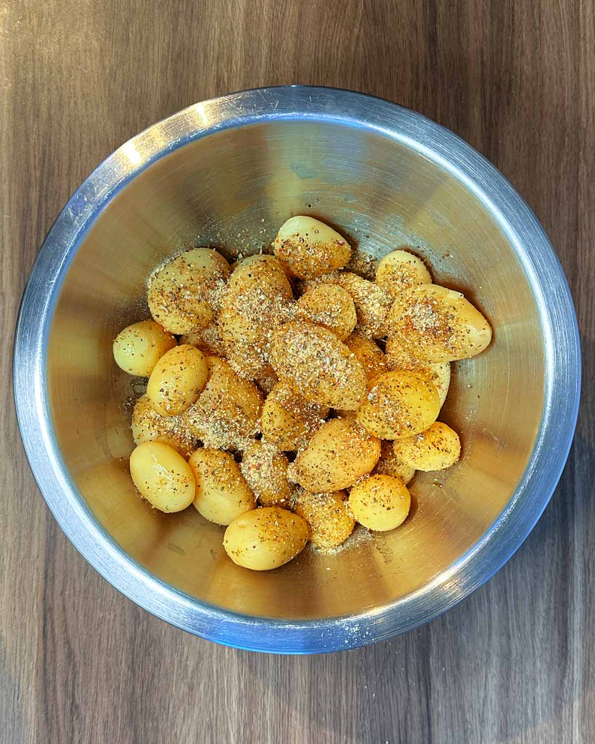 A bowl of new potatoes with oil and seasoning on them.