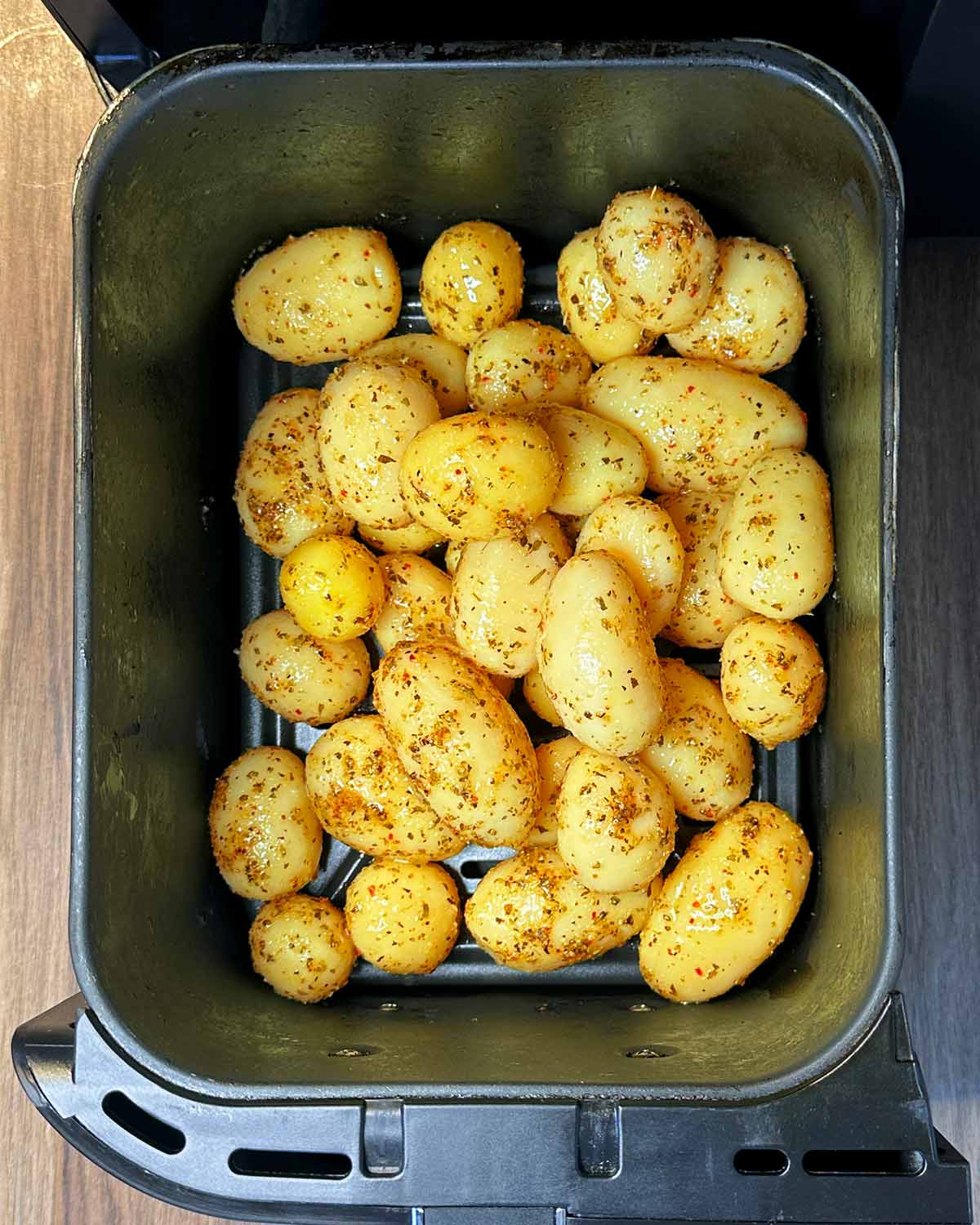 Seasoned new potatoes in an air fryer basket.