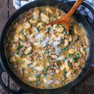 Creamy sausage gnocchi in a large black pan.