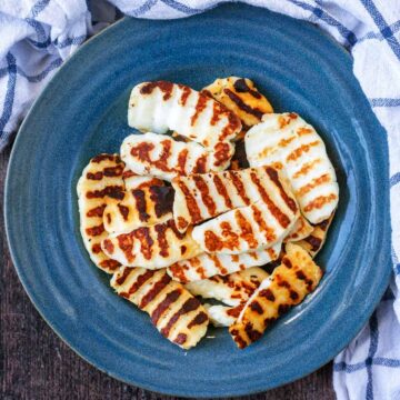 Slices of cooked halloumi on a blue plate.
