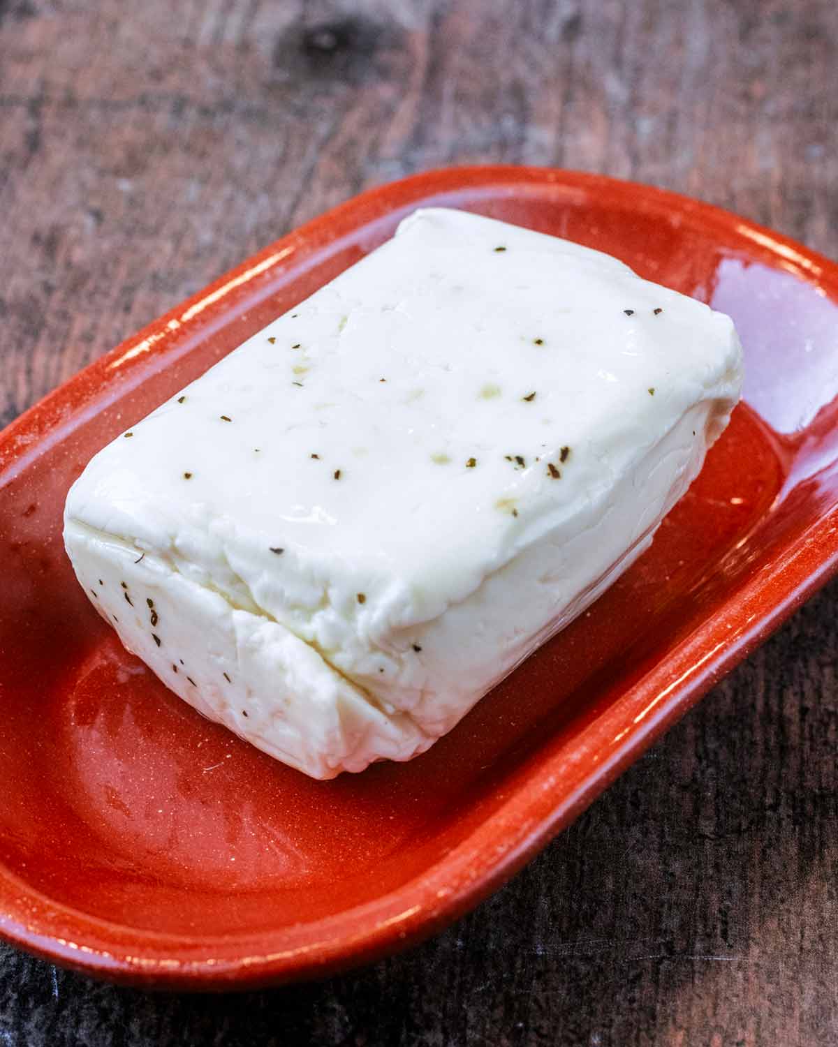 A block of halloumi on a red plate.
