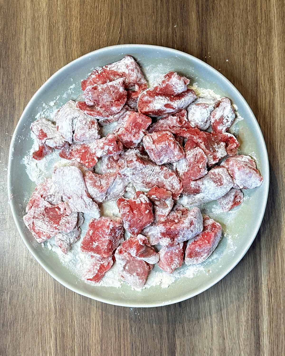 A plate of beef chunks coated in flour.