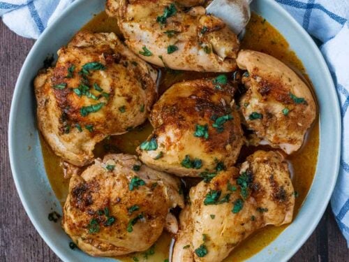 Six slow cooker chicken thighs in a round dish.