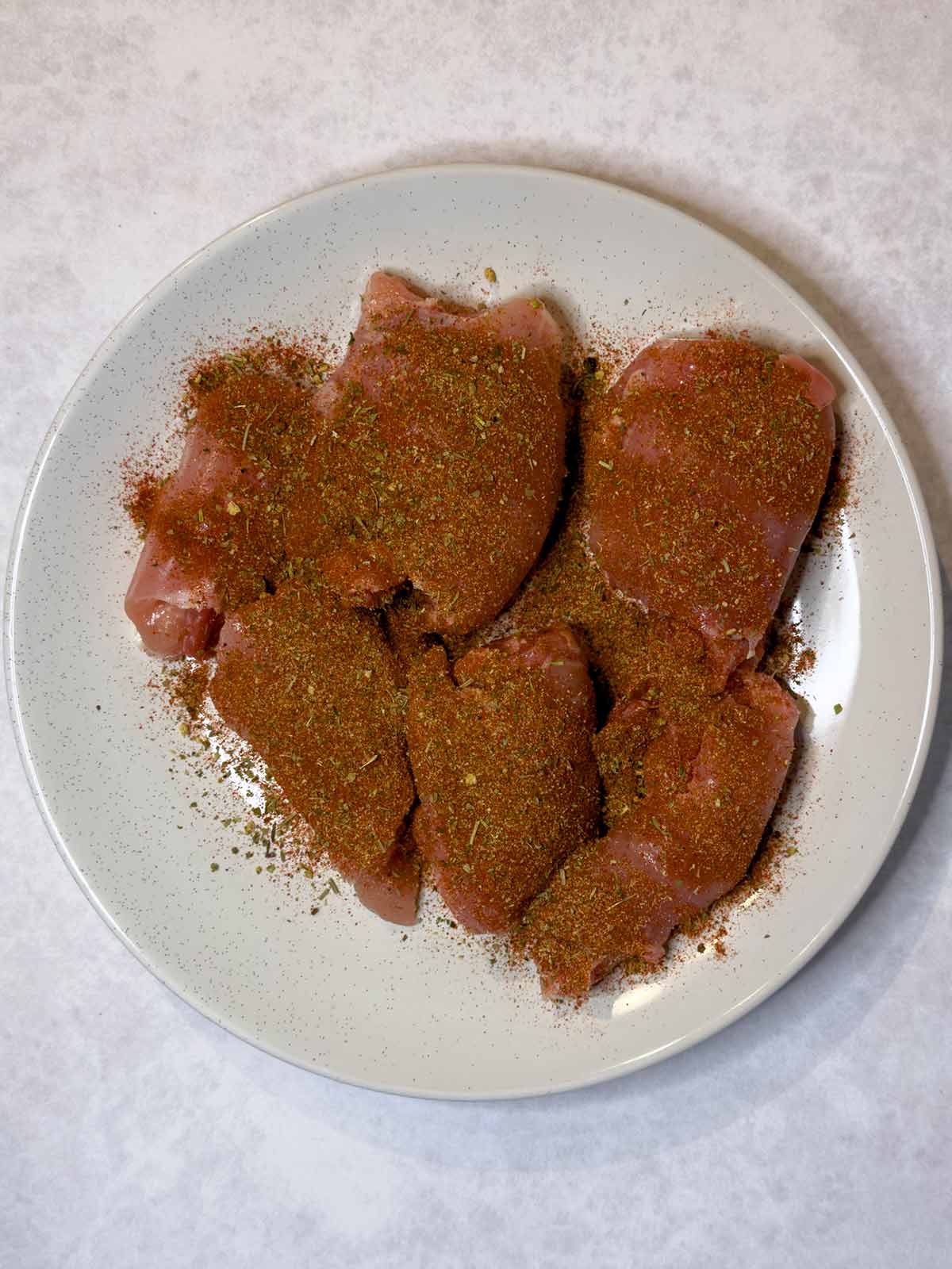 Raw chicken thighs coated in a spice rub.