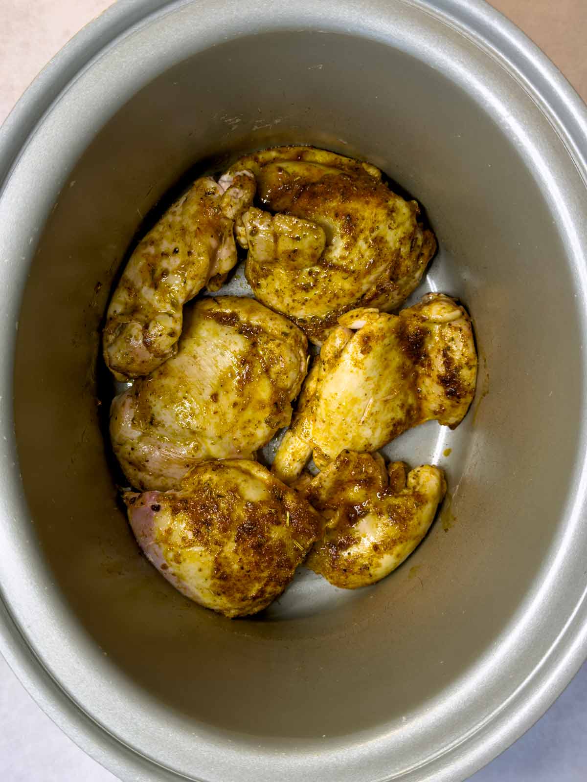 Part cooked chicken thighs in a slow cooker.