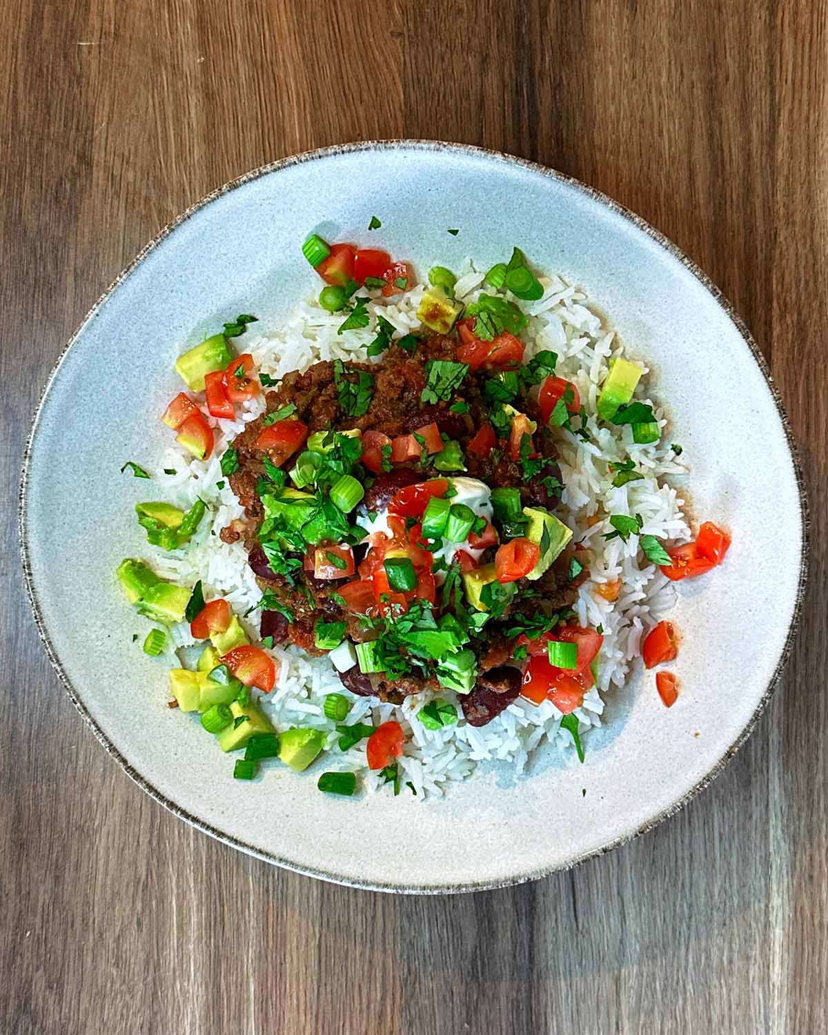 Chilli on rice topped with avocado, tomatoes, spring onions and coriander.