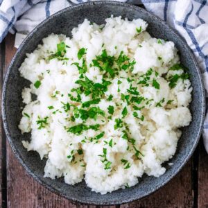 A bowl of slow cooker rice topped with chopped herbs.