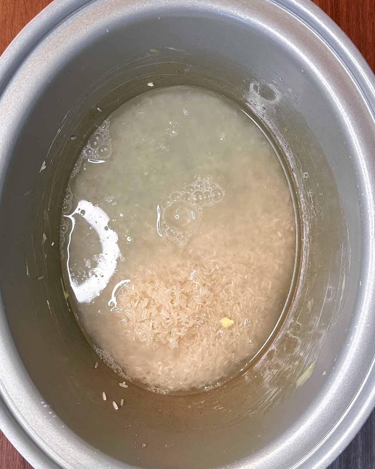 Rice and water in a slow cooker bowl.