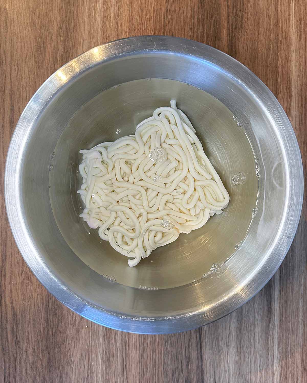 Udon noodles soaking in a bowl of water.