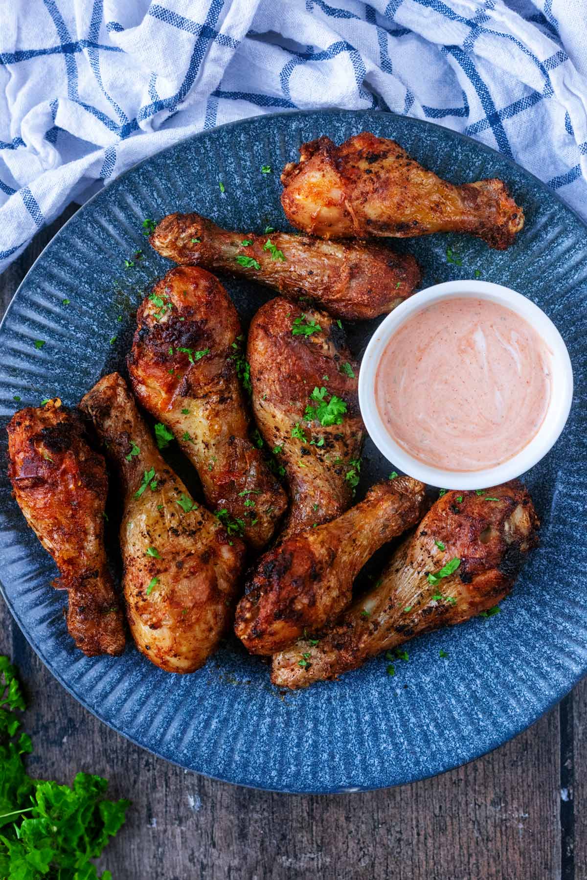 A plate of cooked chicken drumsticks with a pot creamy sauce.