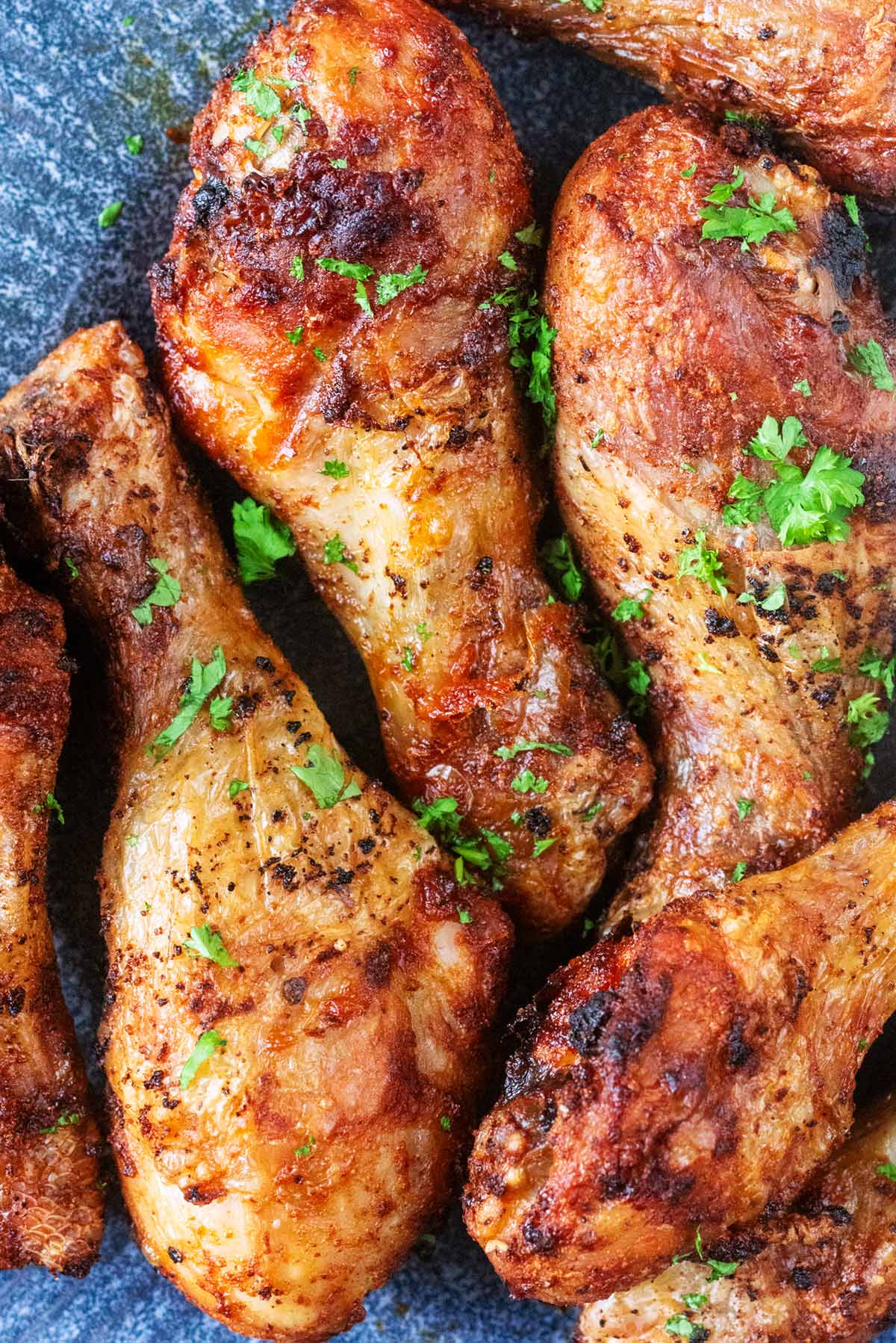 Cooked chicken drumsticks with chopped herbs sprinkled on them.