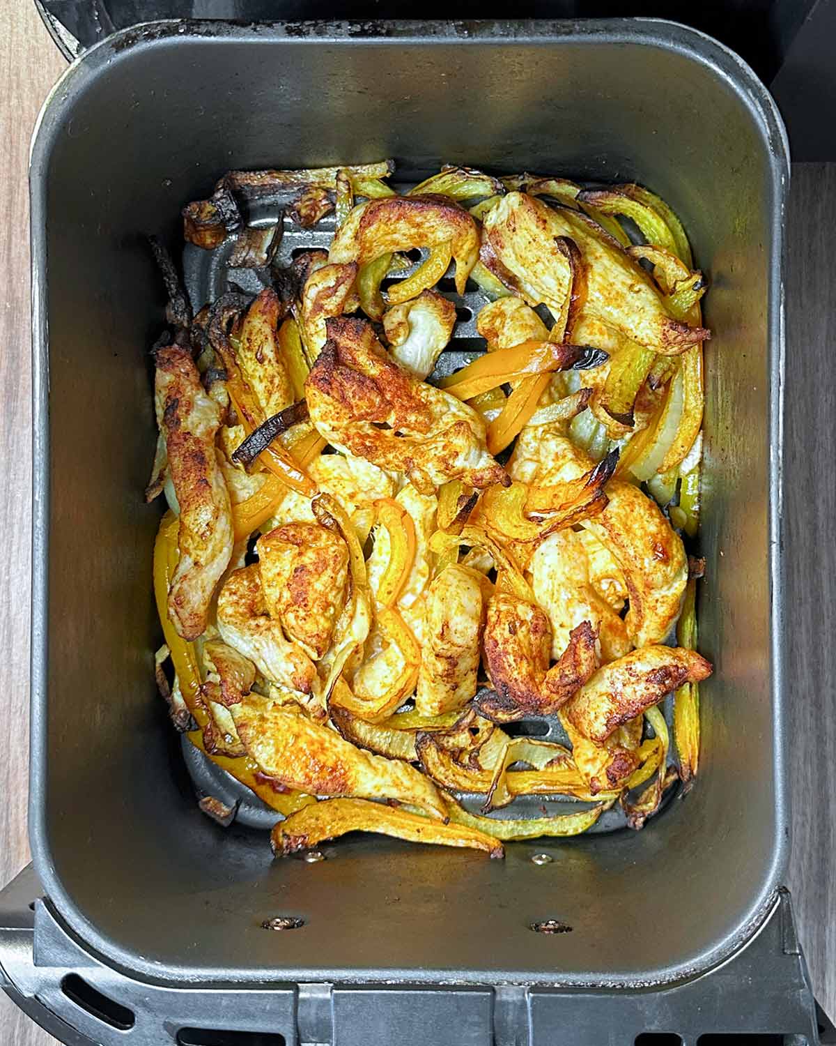 Cooked chicken, peppers and onions in an air fryer.
