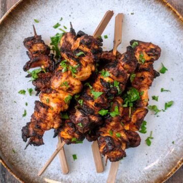 Air fryer chicken kebabs piled up on a grey plate.