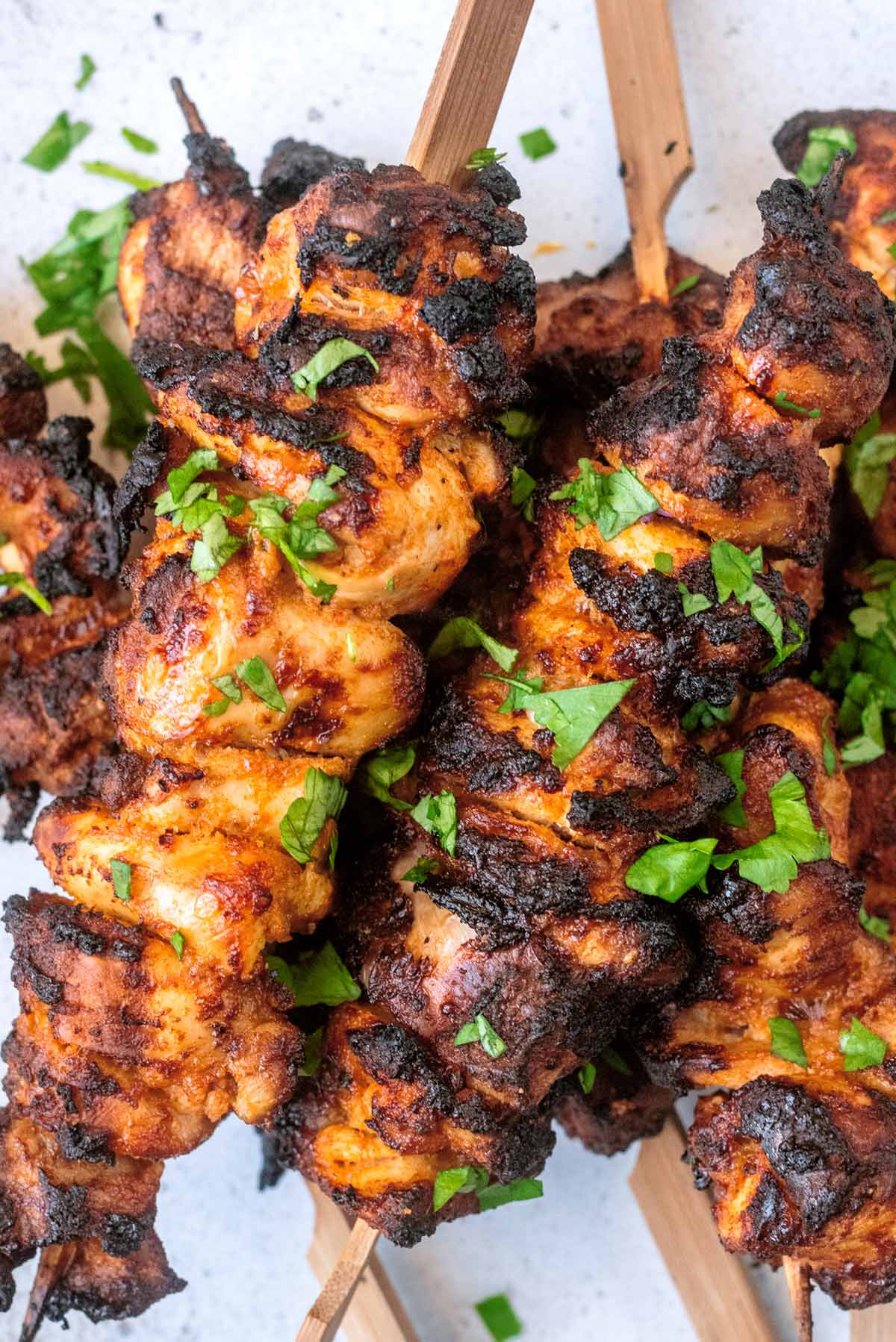 Chicken skewers with chopped herbs scattered over them.