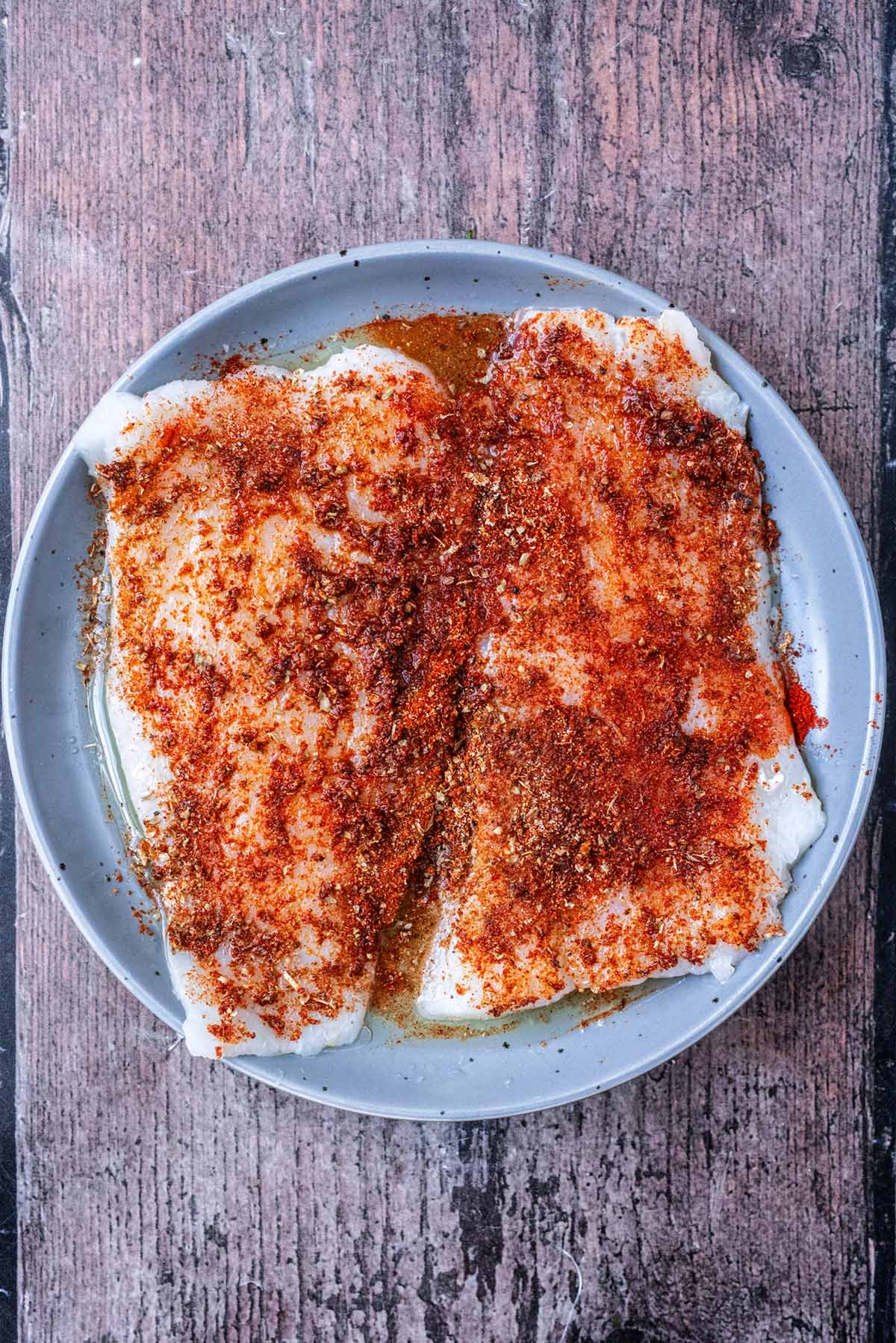 Two cod fillets coated in a spice blend.