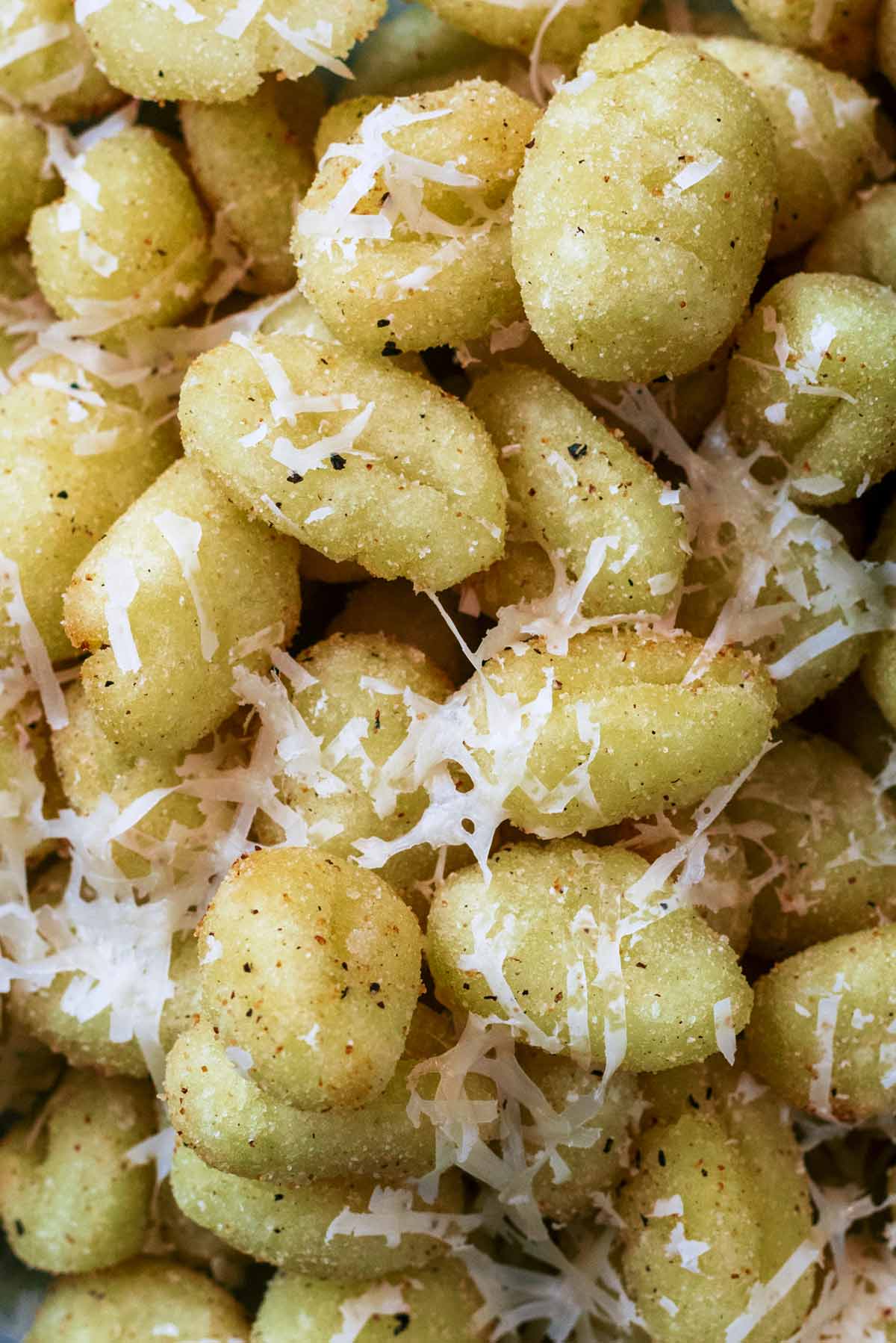 Cooked gnocchi with shavings of Parmesan melting on it.