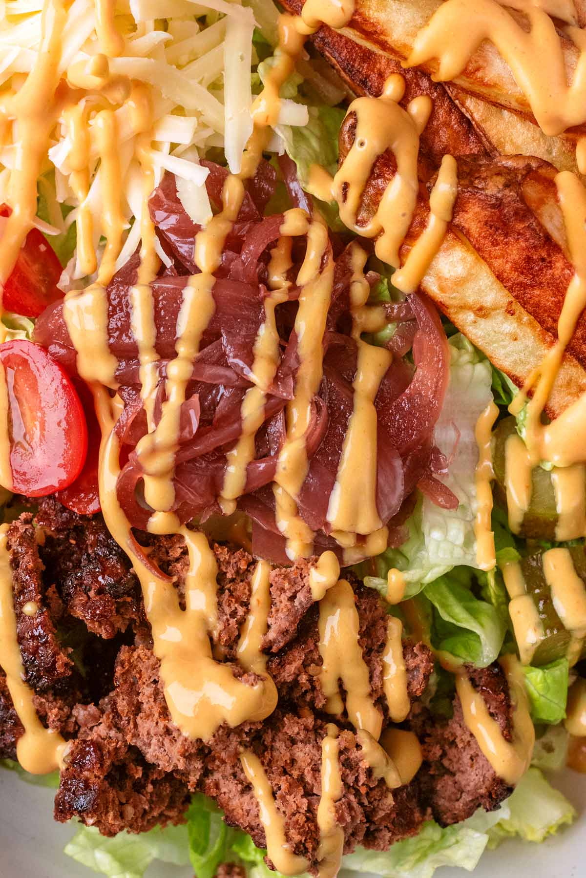 Burger sauce drizzled over chopped up burger and salad.