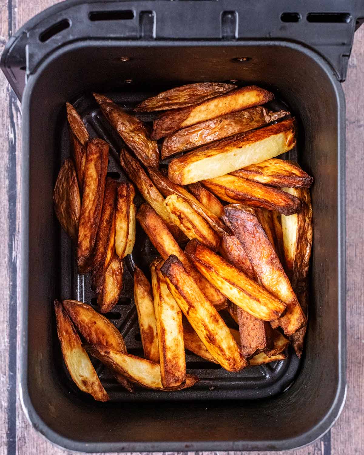 Cooked chips in an air fryer basket.