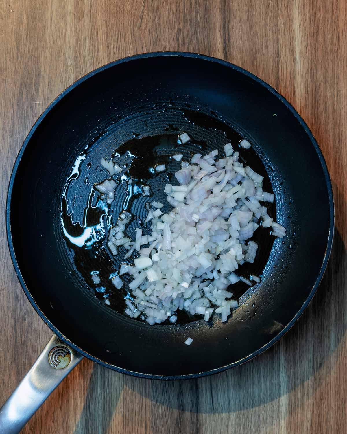 Chopped shallots cooking in a frying pan.