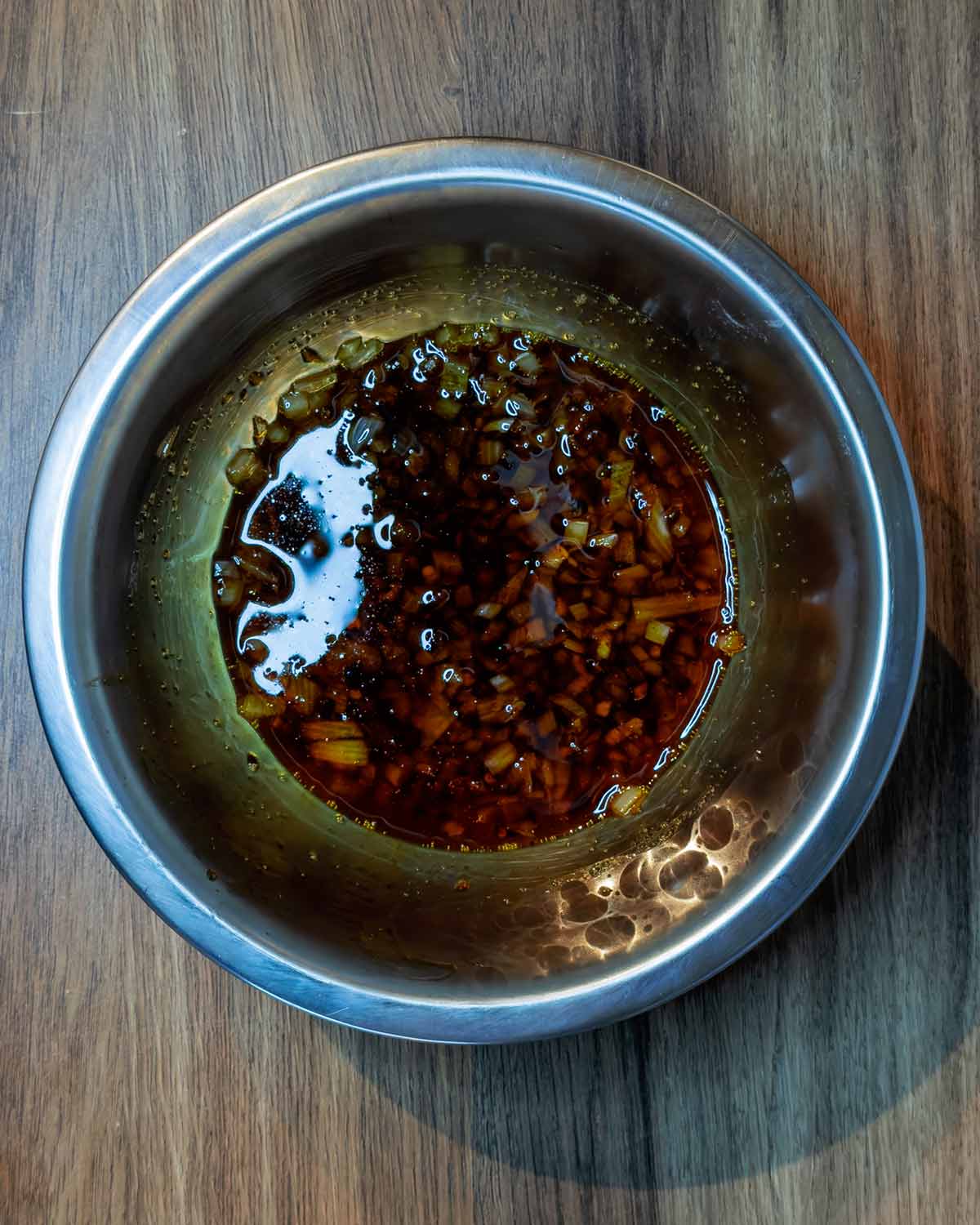 A mixing bowl containing the cooked shallots, oil, honey and soy sauce.